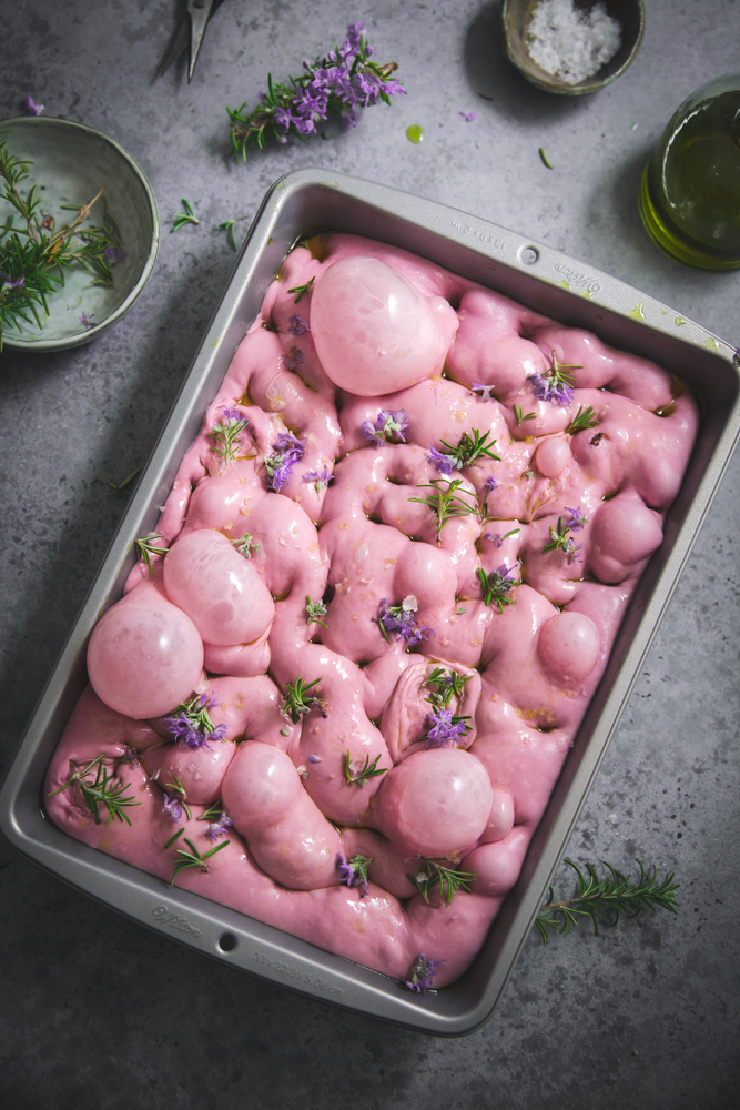 Focaccia mille bolle rosa con patate viola e fiori di rosmarino